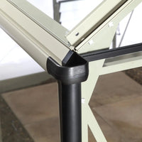 A Rhino Greenhouse corner section with beige aluminum frame and a black plastic connector, set in a garden with tiled flooring, showcasing structural design and material details.