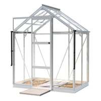 A white-framed glass Rhino Greenhouse stands with an open door, showcasing a paved interior against a plain white background.