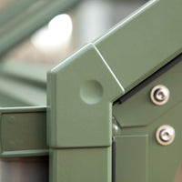 Green metal frame, secured with bolts, forms part of a Rhino Greenhouse structure. The angle highlights the intersection of two bars, with a blurred background suggesting an indoor or covered setting.