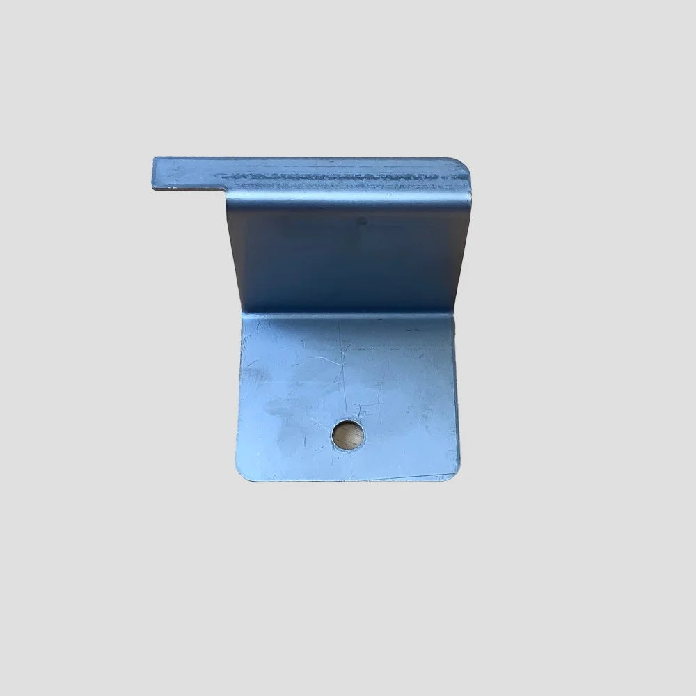 A metallic bracket with a right-angle bend and a hole in the flat base lies on a plain gray background, likely used for structural support or fastening.
