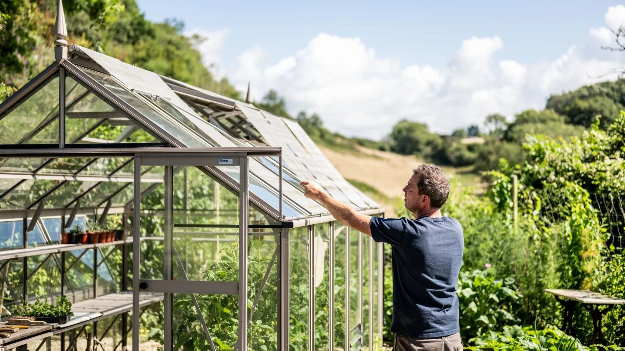 Man pulling down Rhino Roof Blinds to shade his greenhouse