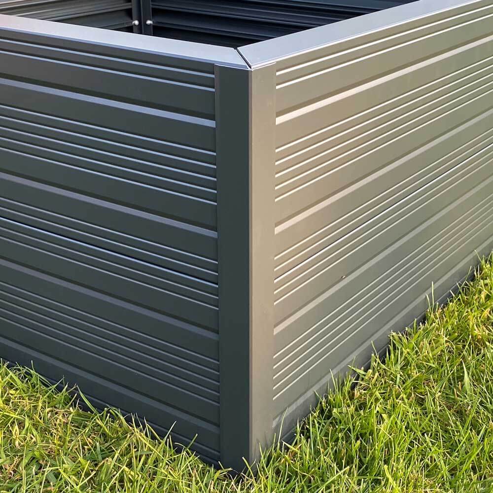 Metal planter box with horizontal grooves stands on grass, showcasing a sturdy, modern design suitable for gardening.